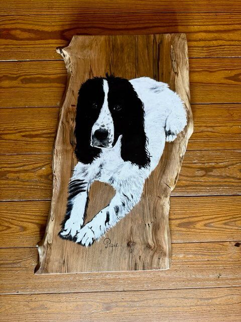 A wooden stick with two cardinals painted on it is sitting on a wooden floor.
