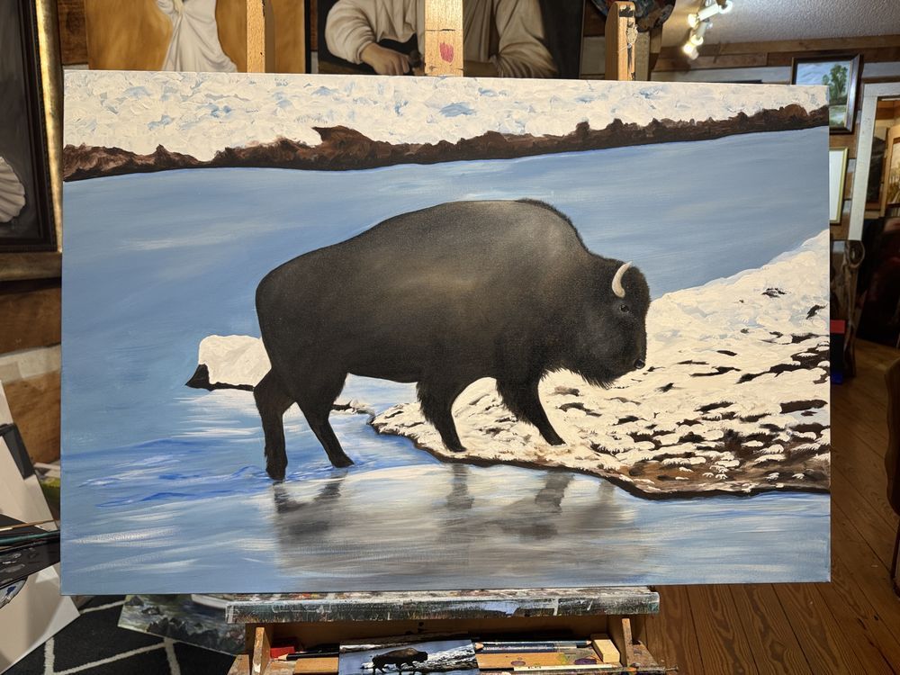 A painting of a bison standing in the water on an easel.