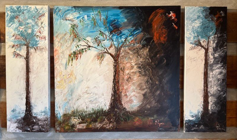 Three paintings of trees are hanging on a wall.