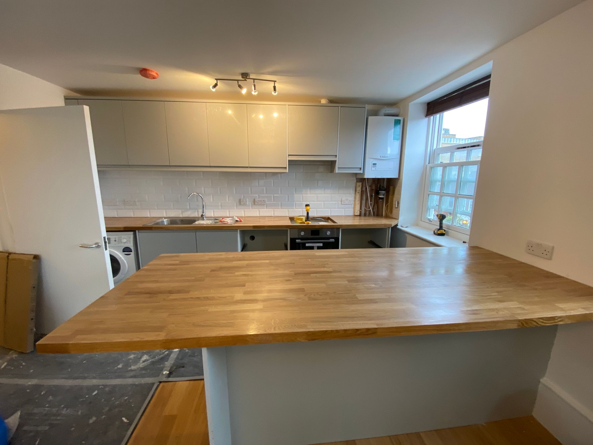 Spacious kitchen with breakfast bar and modern grey units in a finished Hackney E5 apartment renovation.