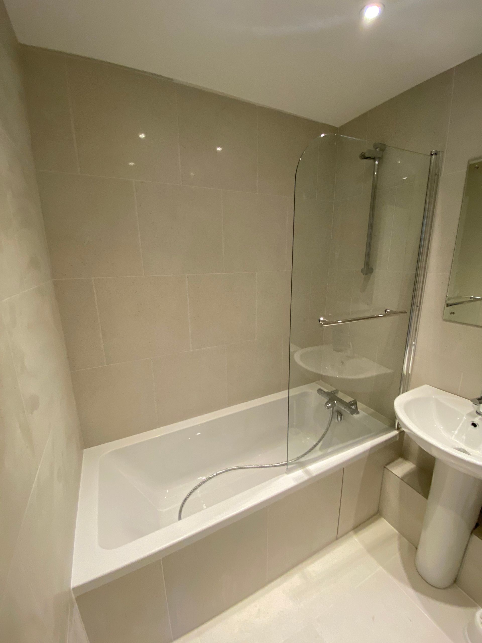 Contemporary grey wall tiling and glass shower screen in a finished Hackney E5 bathroom.