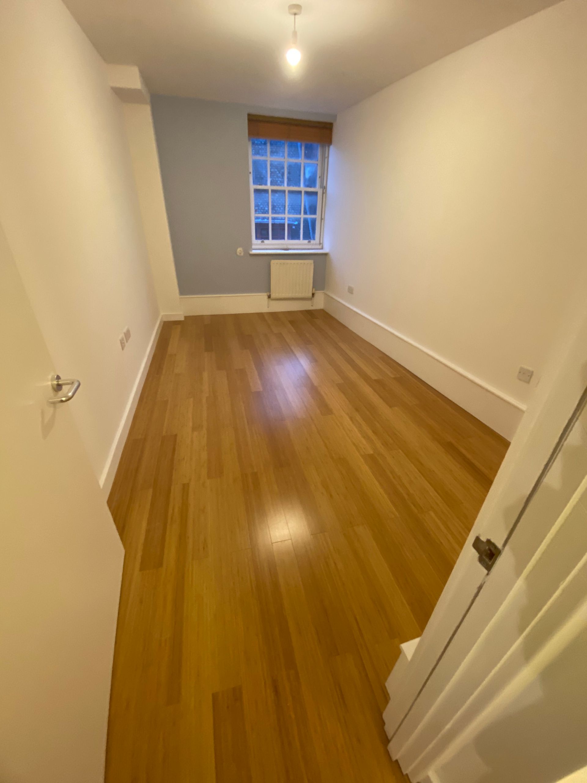 Empty bedroom with wood flooring and natural light in a completed Hackney E5 apartment refurbishment.