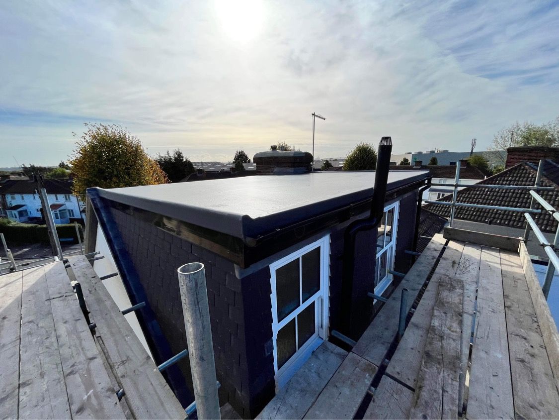 Wide-angle view of a new flat-roof loft extension with modern windows and black exterior finish.
