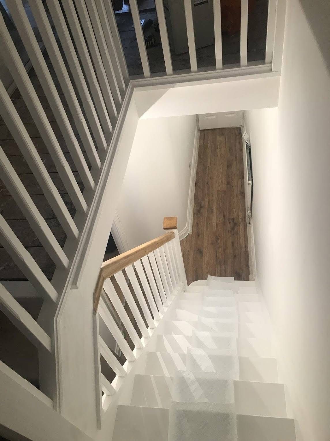 View looking up at a newly painted staircase and landing in the renovated home.