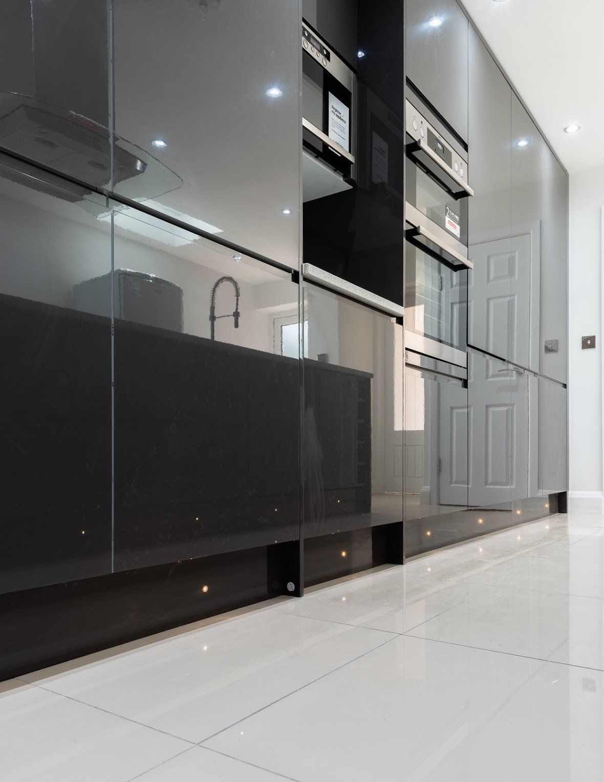 eflection in high-gloss designer kitchen cabinetry in a Walthamstow E17 renovation by Ibex Builders.