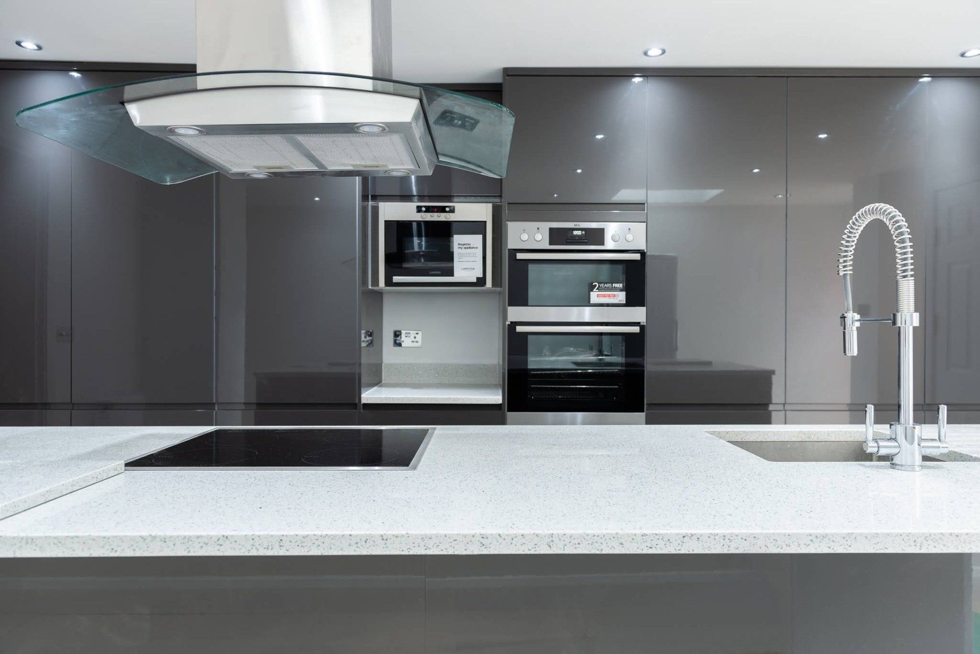 High-gloss grey kitchen cabinets and integrated ovens in a Walthamstow extension by Ibex Builders.