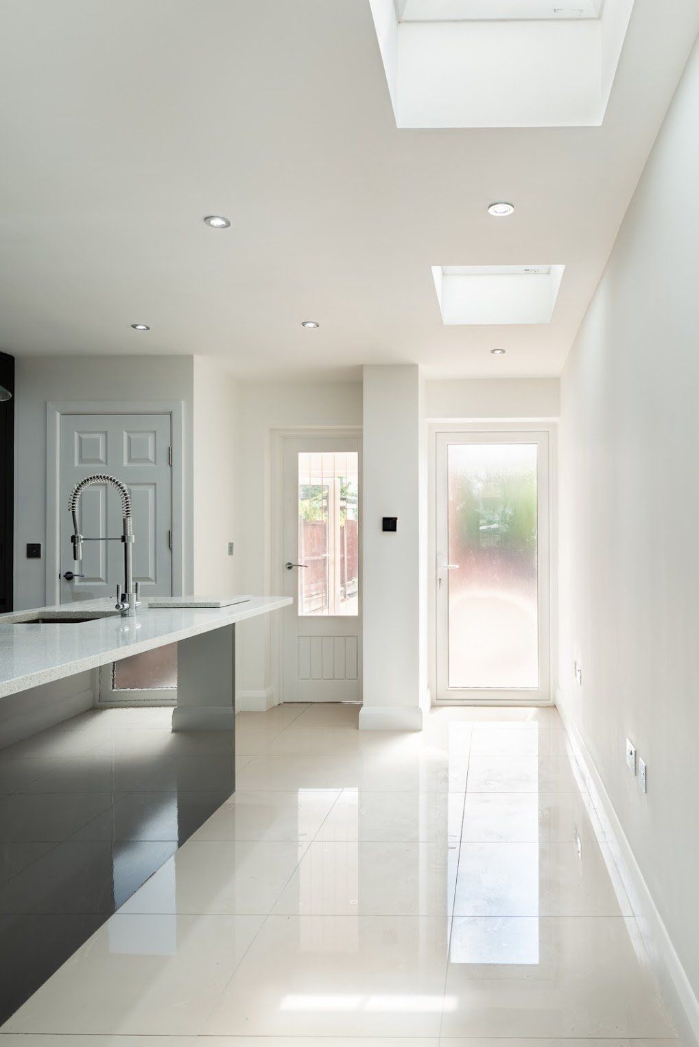 Clean, minimalist ceiling design with integrated lighting and skylights in a Walthamstow extension by Ibex Builders.