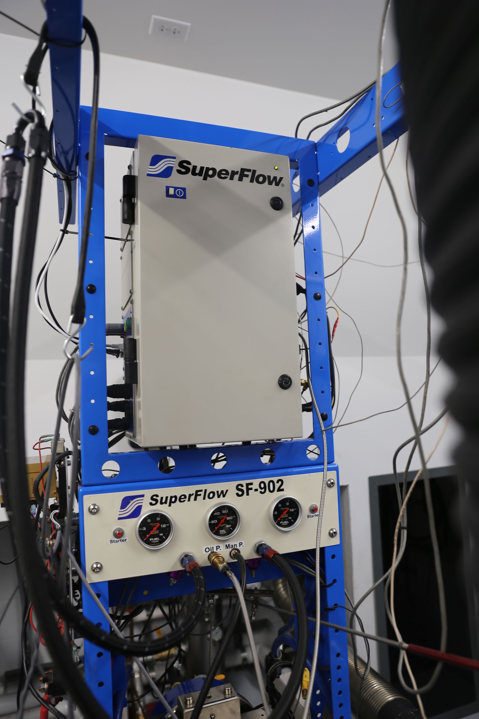 Blue metal frame with a SuperFlow SF-902 control panel, gauges, and electrical components.