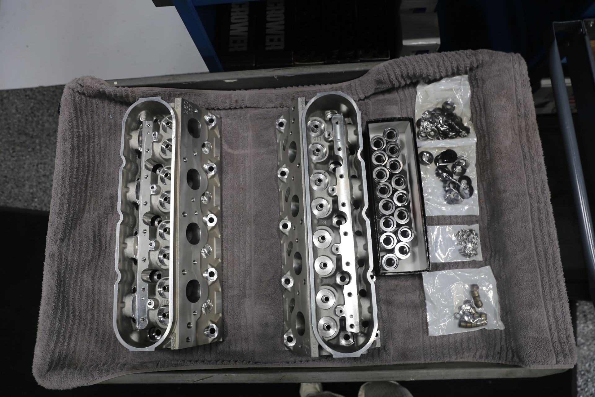 Two disassembled engine cylinder heads and hardware laid out on a towel.