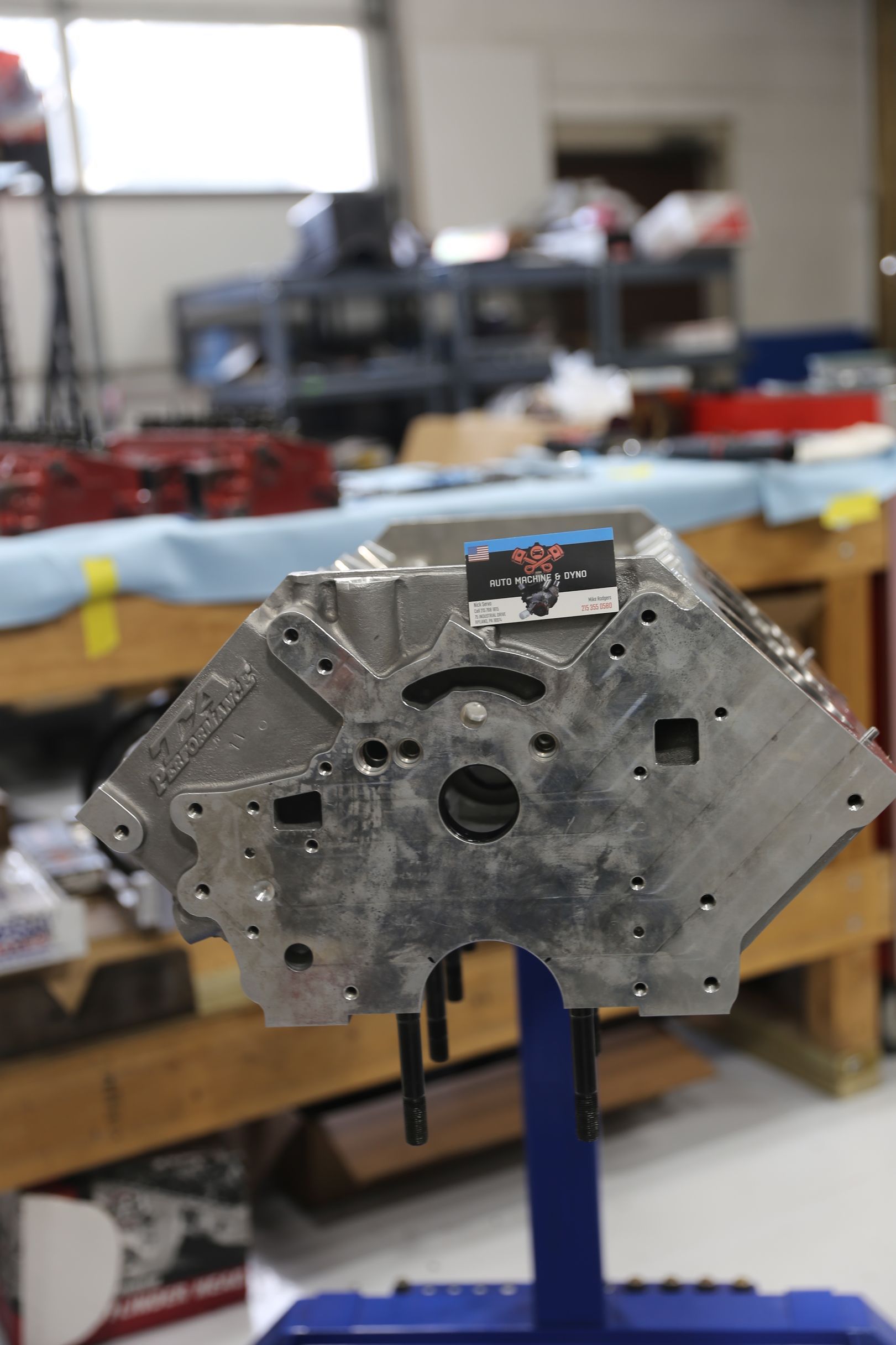 Aluminum engine block on a stand in a workshop, showcasing the bottom with various holes.