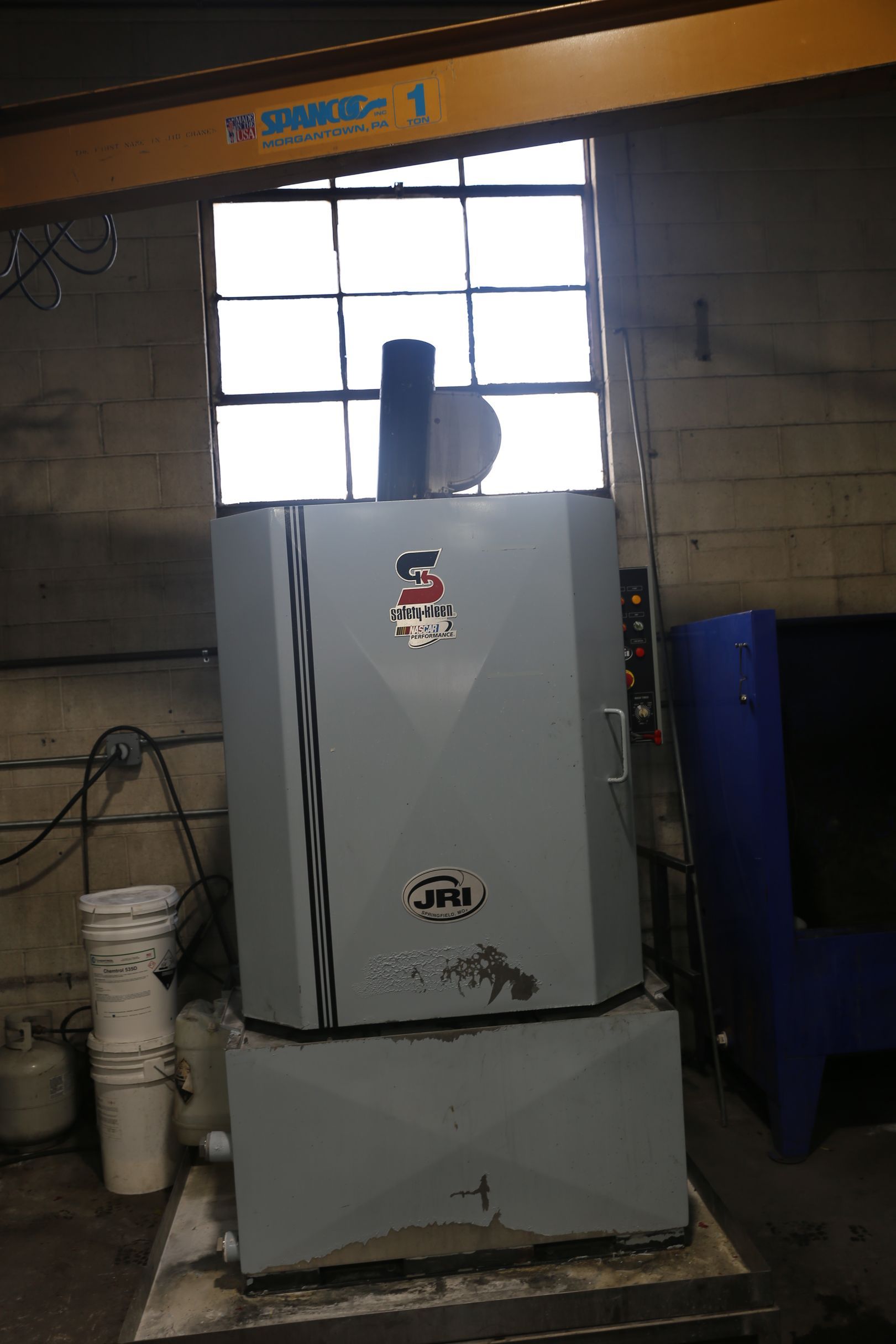 Large gray industrial oven in a workshop, with a window behind it.
