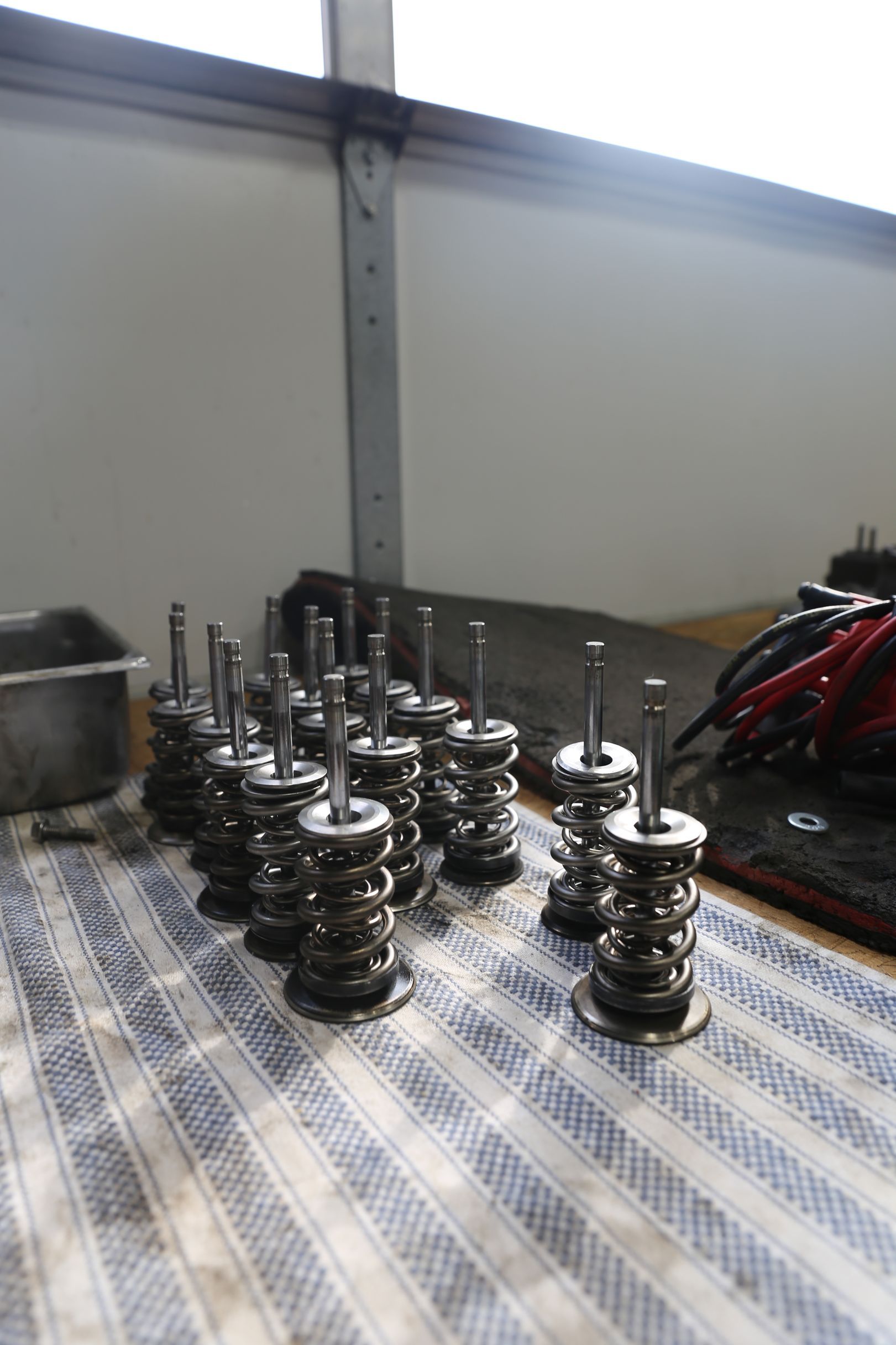 Several assembled engine valve springs and components arranged on a table covered with a checkered cloth.