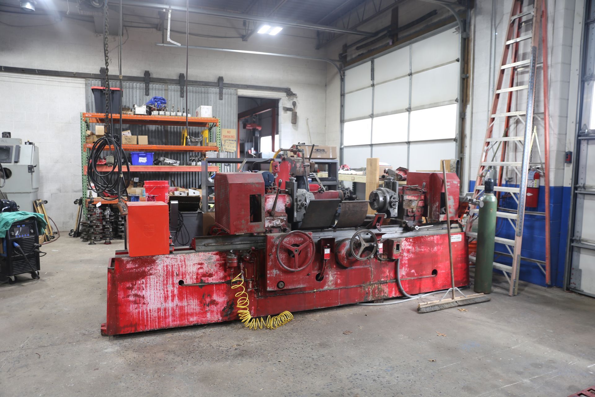 Red industrial grinding machine in a workshop.