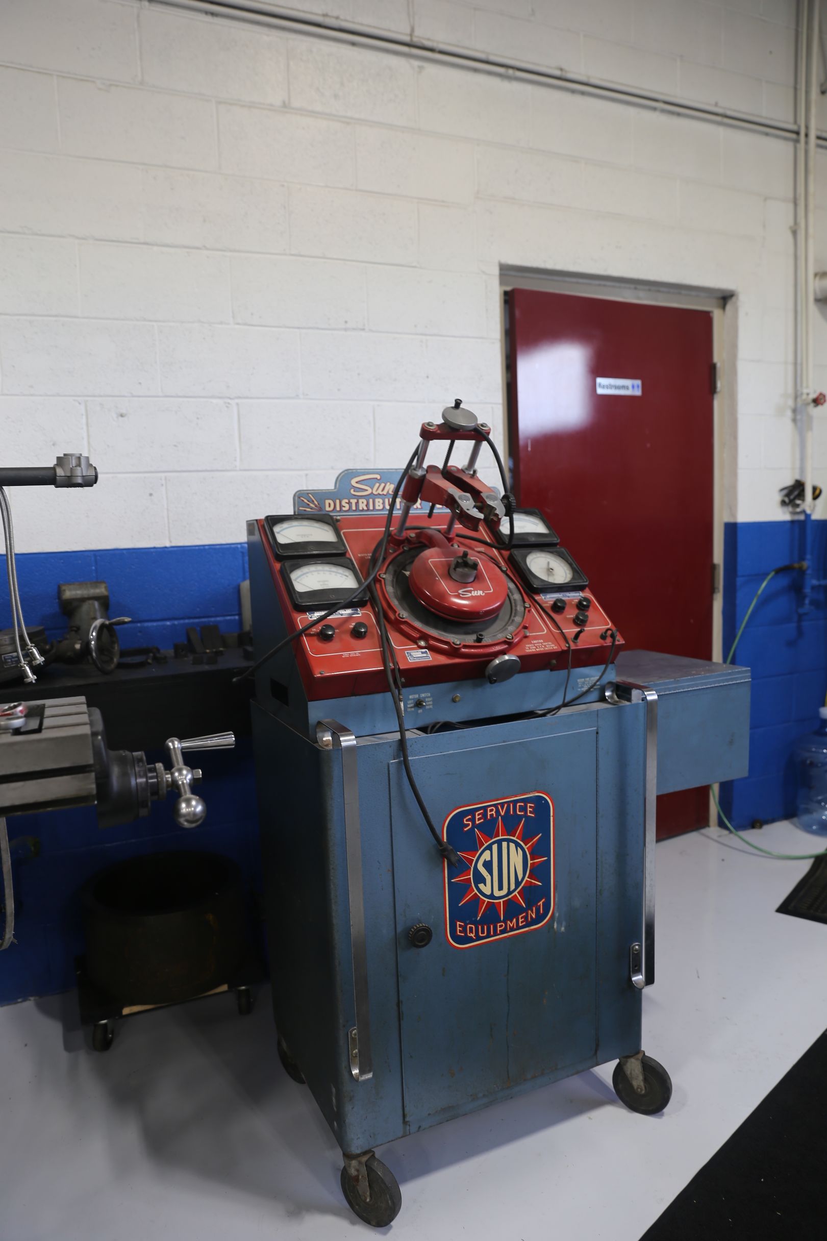 Blue and red auto diagnostic machine on wheels in a garage.