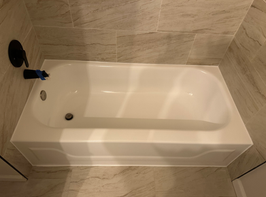 White bathtub with black faucet in a tiled bathroom.