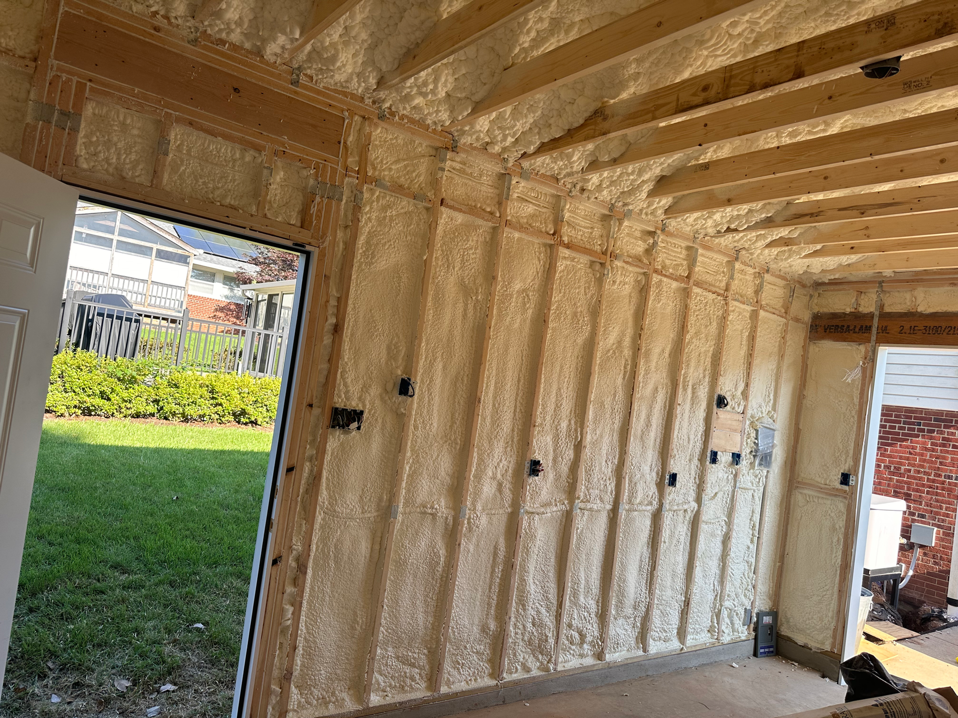 Interior view of a room under construction with spray foam insulation on the walls and ceiling.