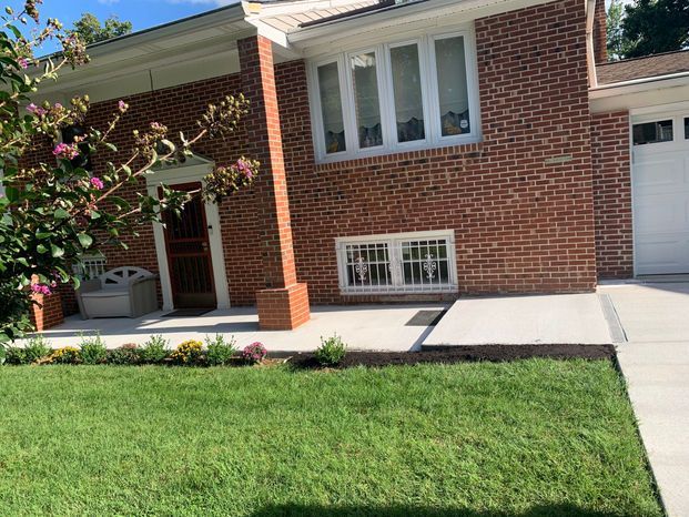 Brick house with a green lawn and concrete pathway.