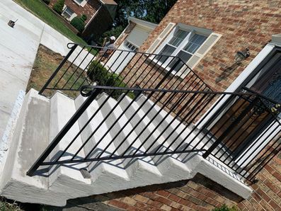 Exterior staircase with black metal railings and a brick house.