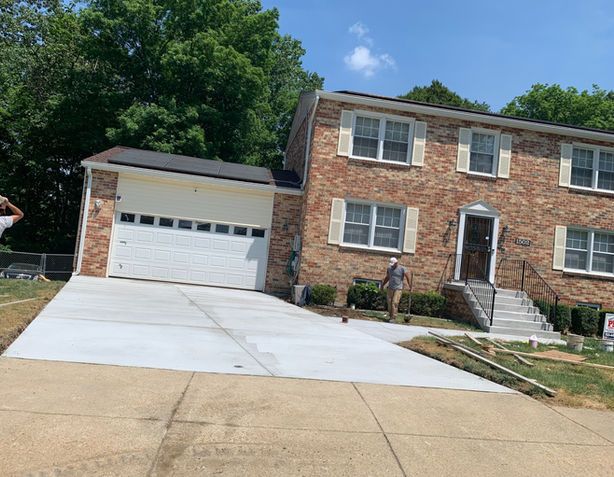 Brick house with a new concrete driveway and two people present.