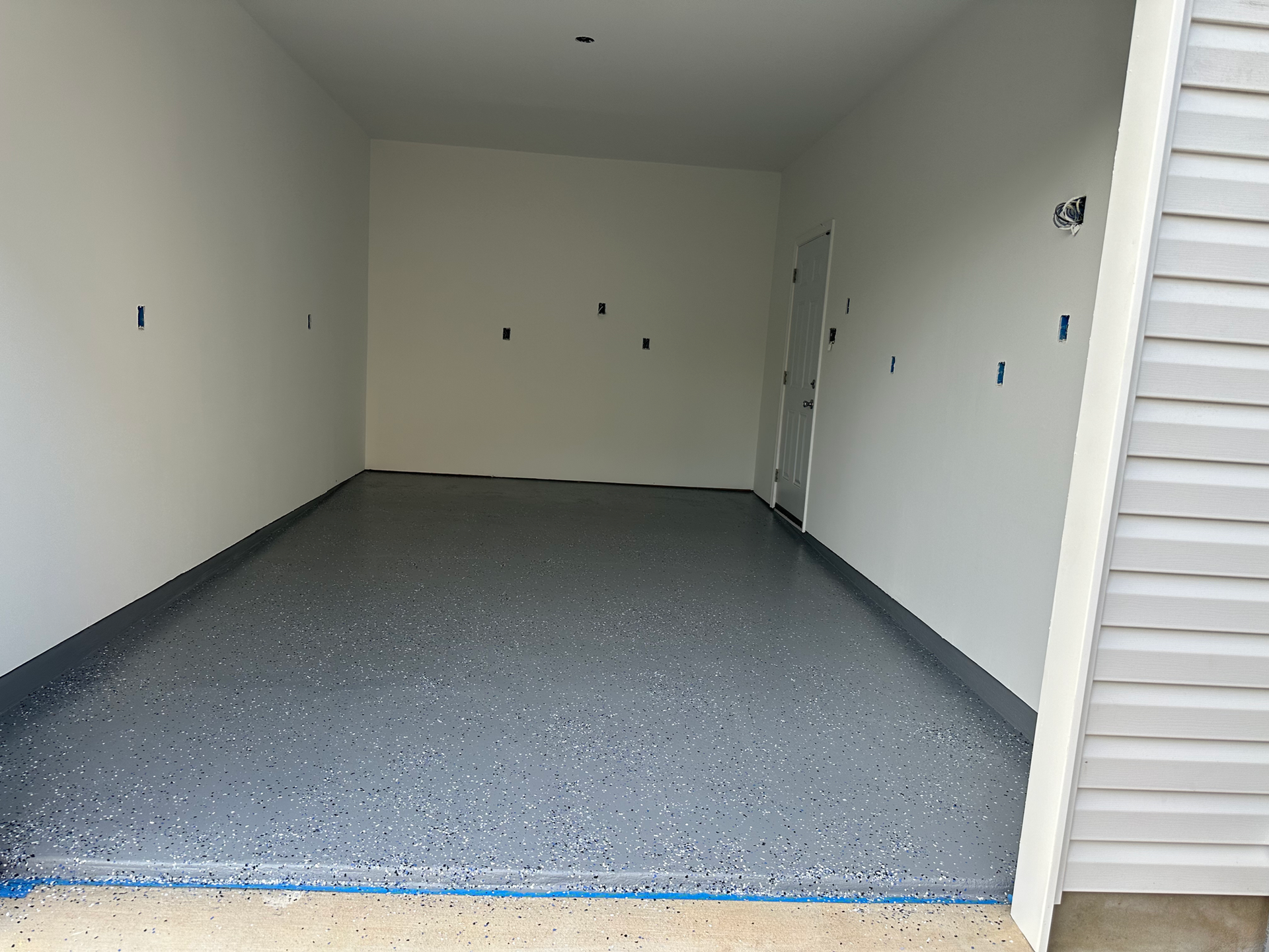 Empty garage with gray speckled floor and white walls.