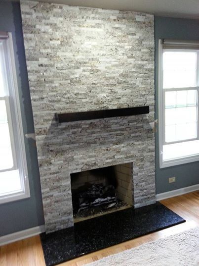 Gray stone fireplace with dark wood mantel, black hearth, and windows on either side.