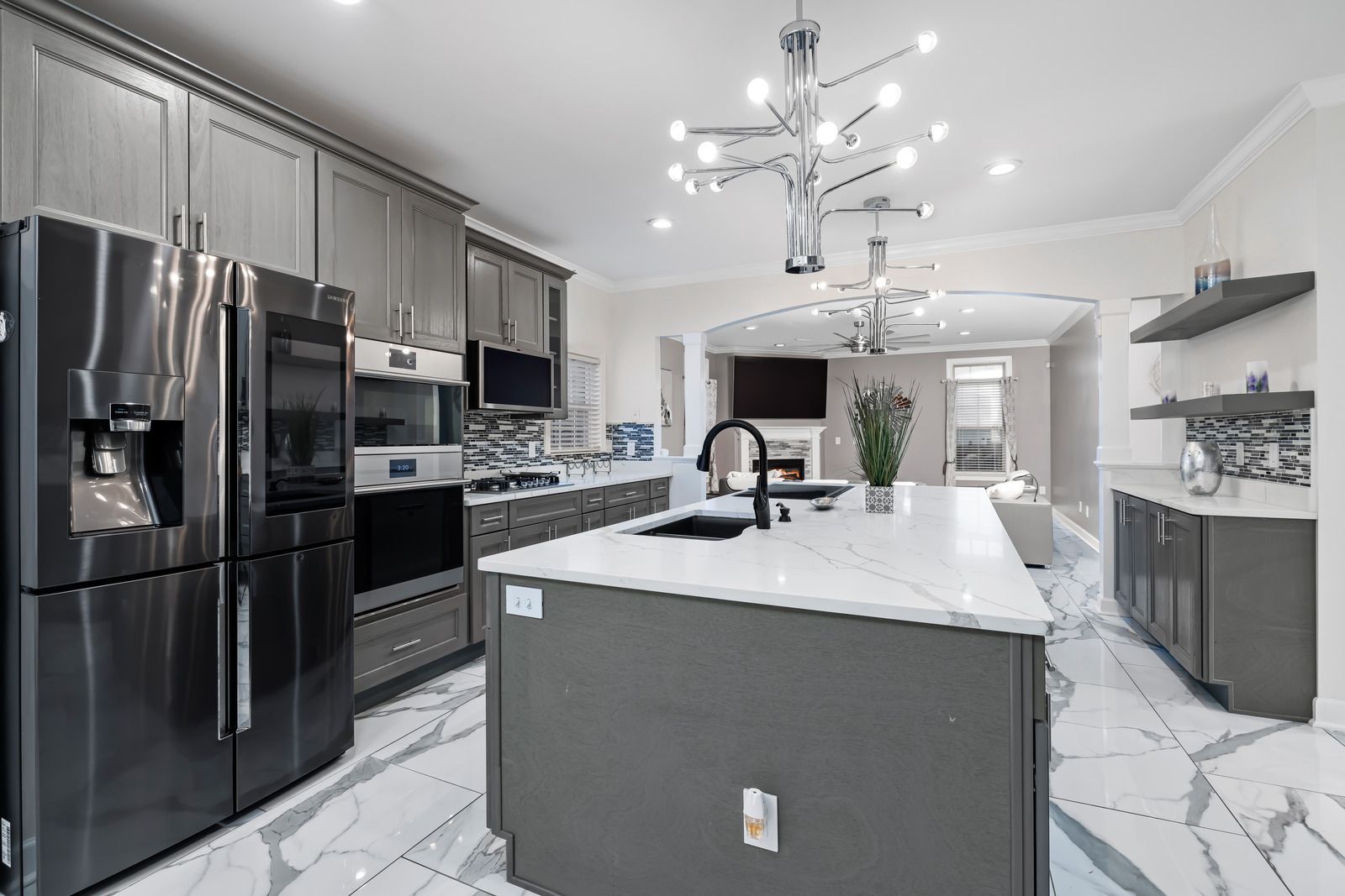 Modern gray kitchen with island and marble floors; leads to a living area.