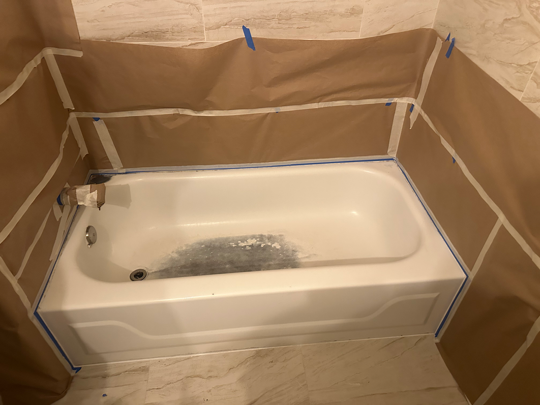 Bathtub with taped-off walls, likely in preparation for painting or renovation, bathroom setting.