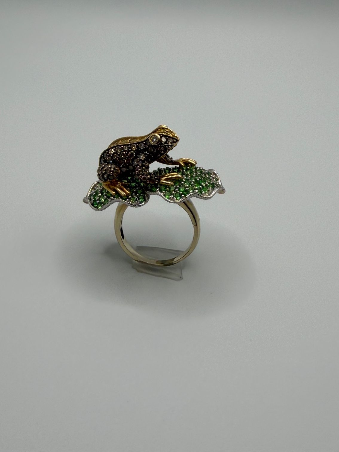 Gold ring with a small leopard-shaped design on green and dark enameled leaves