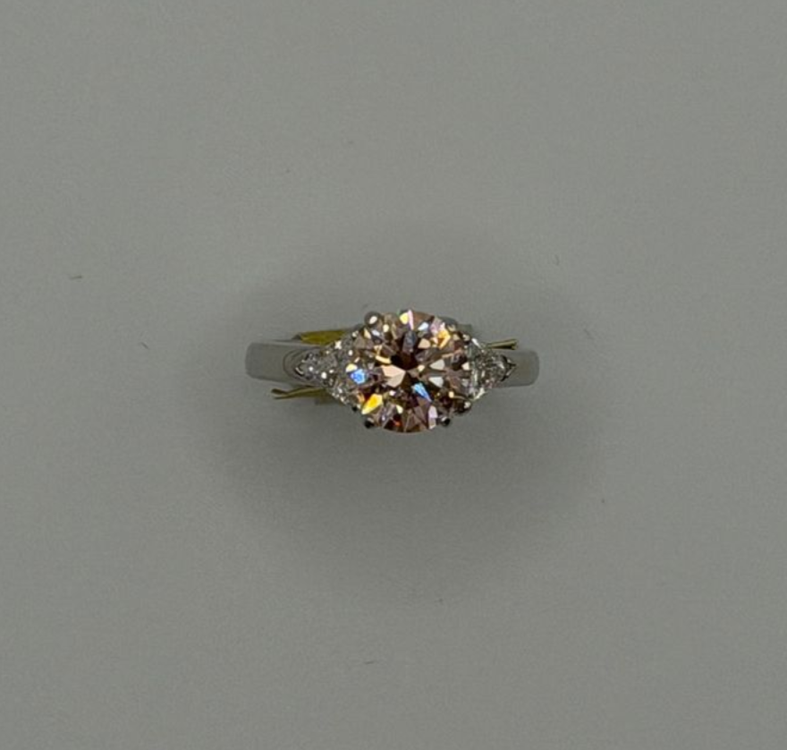 Silver ring with a round, multi-stone gemstone centerpiece on a plain gray background