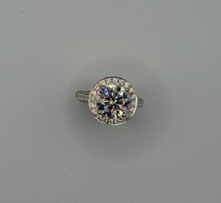 Round diamond engagement ring with halo setting on a light gray background