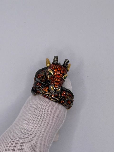 Small red-and-black dragon figurine perched on a fingertip against a plain background