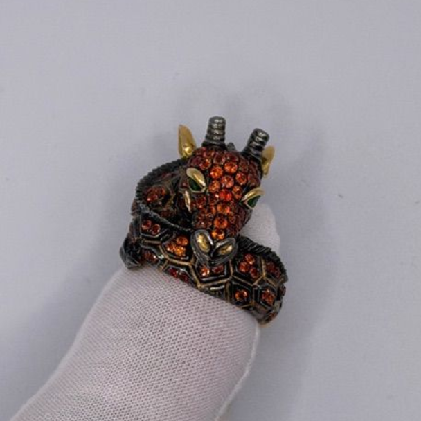 Ring shaped like a coiled dragon with red and black jeweled details on a finger