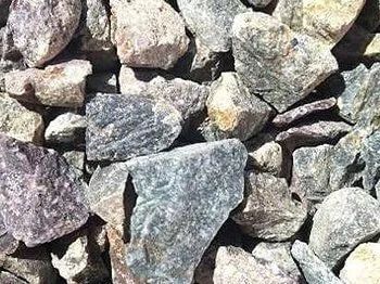 Close-up of a pile of mixed-color gravel, including gray, beige, and purple stones.