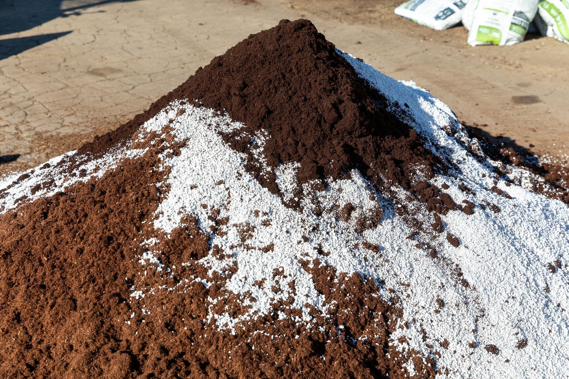 Pile of dark soil mixed with white perlite on a concrete surface.