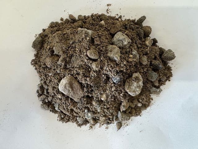 Pile of mixed gravel and sand on a white surface.