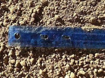 Ruler next to light brown soil with small granules.