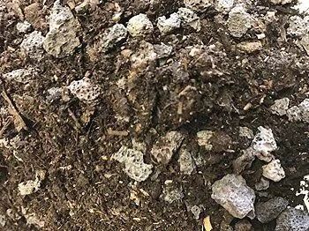 Close-up of a pile of dark soil mixed with gray pumice rocks.
