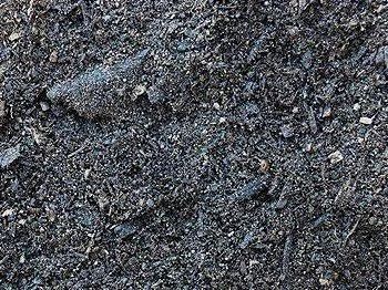 Close-up of dark soil, showing a mix of dark particles and some light-colored specks.