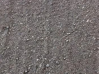 Close-up view of dark gray, granular gravel. Small, light-colored stones are scattered throughout.
