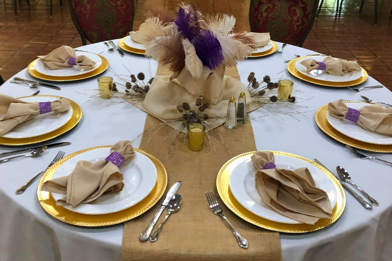 Dining hall set up with long tables, white linens, and flower centerpieces.