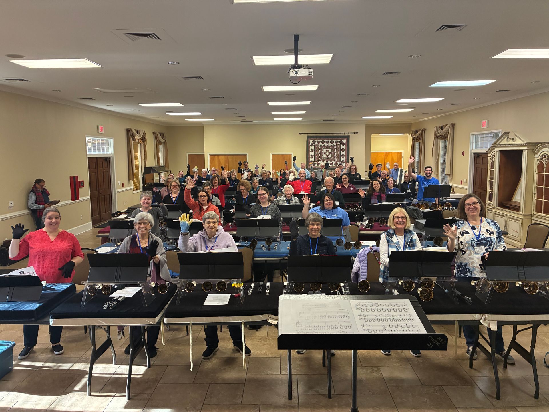 A handbell choir of 30+ people in a large room, ready to perform.