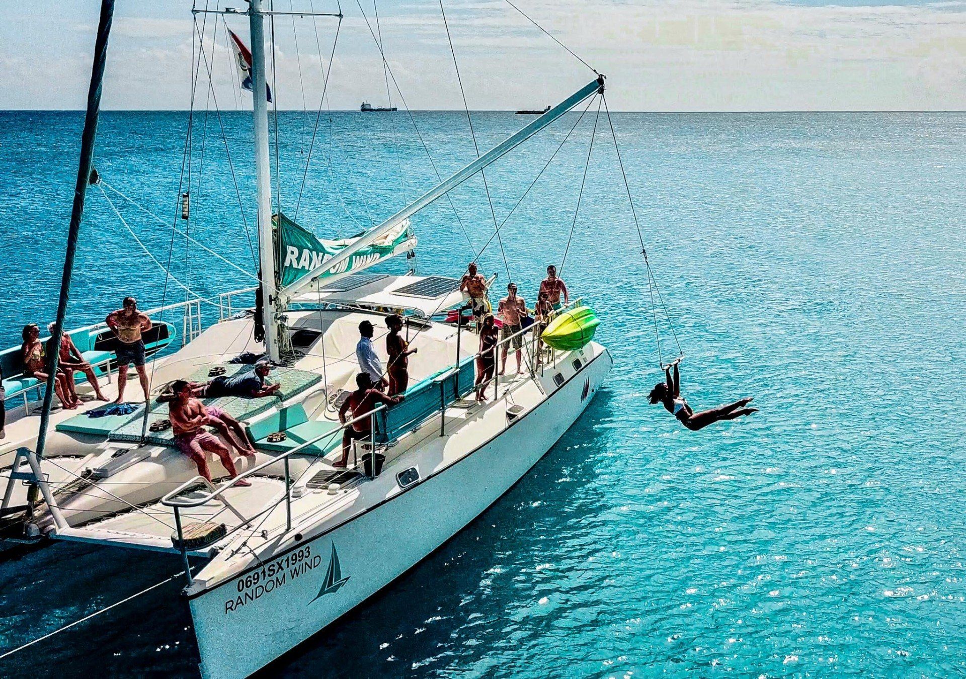 Woman swinging from Random Wind Yacht into the ocean