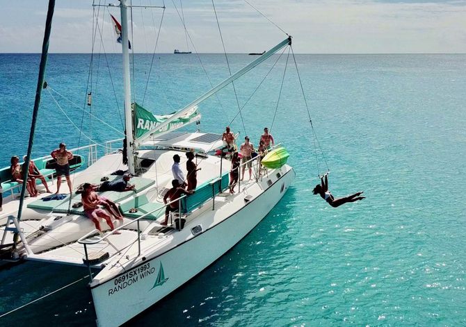 Woman swinging off of Random Wind Yacht