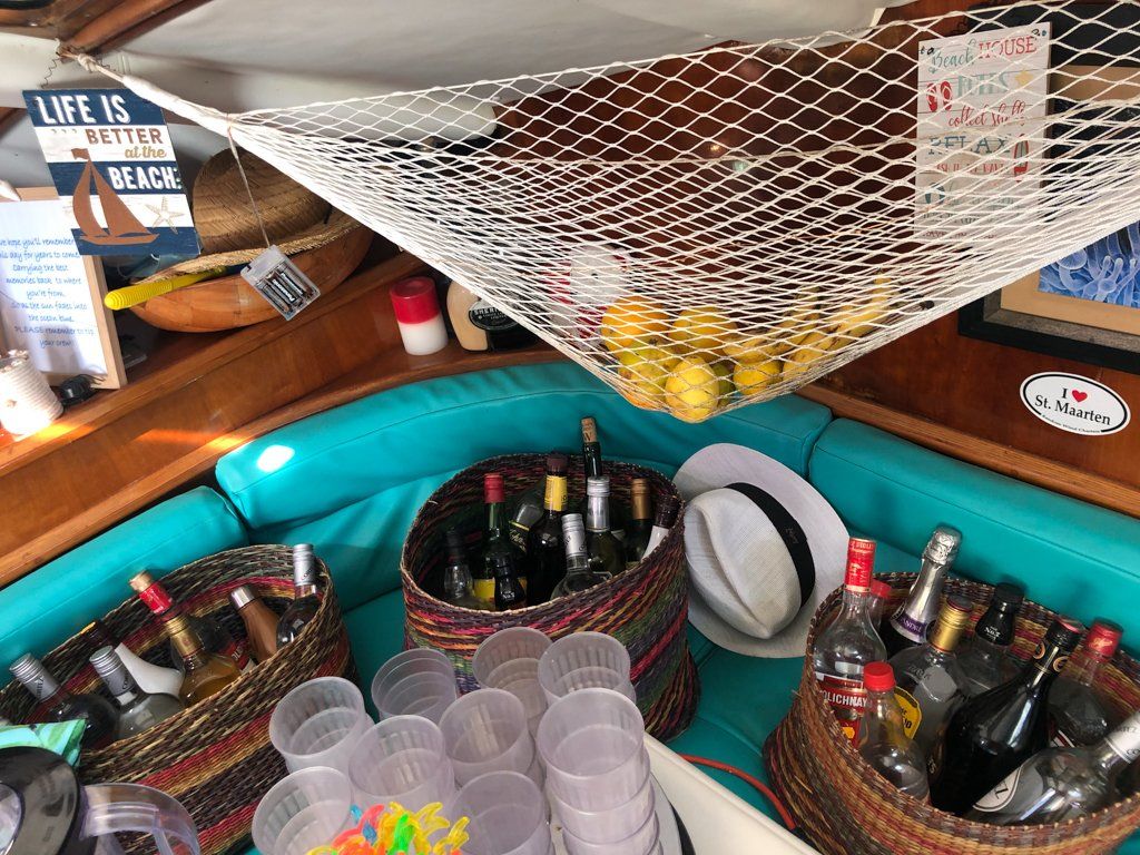 alcohol bottles in baskets with plastic cups and lemons in net above bottles
