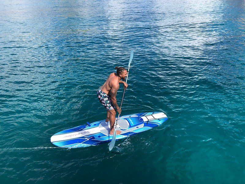 man on blue and white standup paddleboard