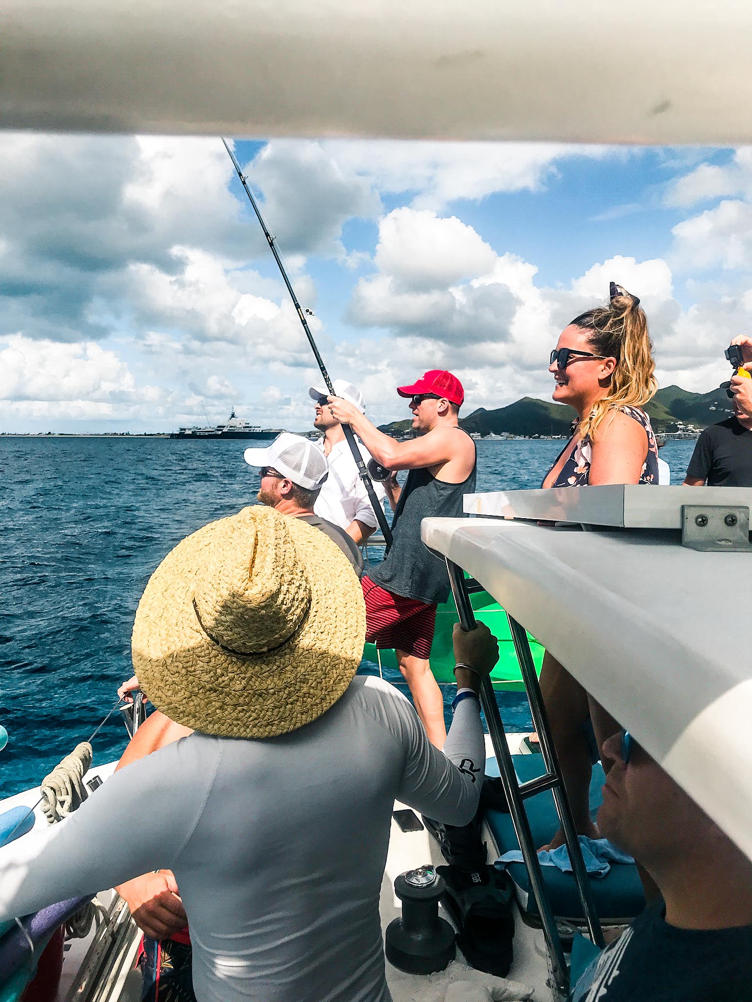 Group of people watching a man fishing from the Random Wind Yacht