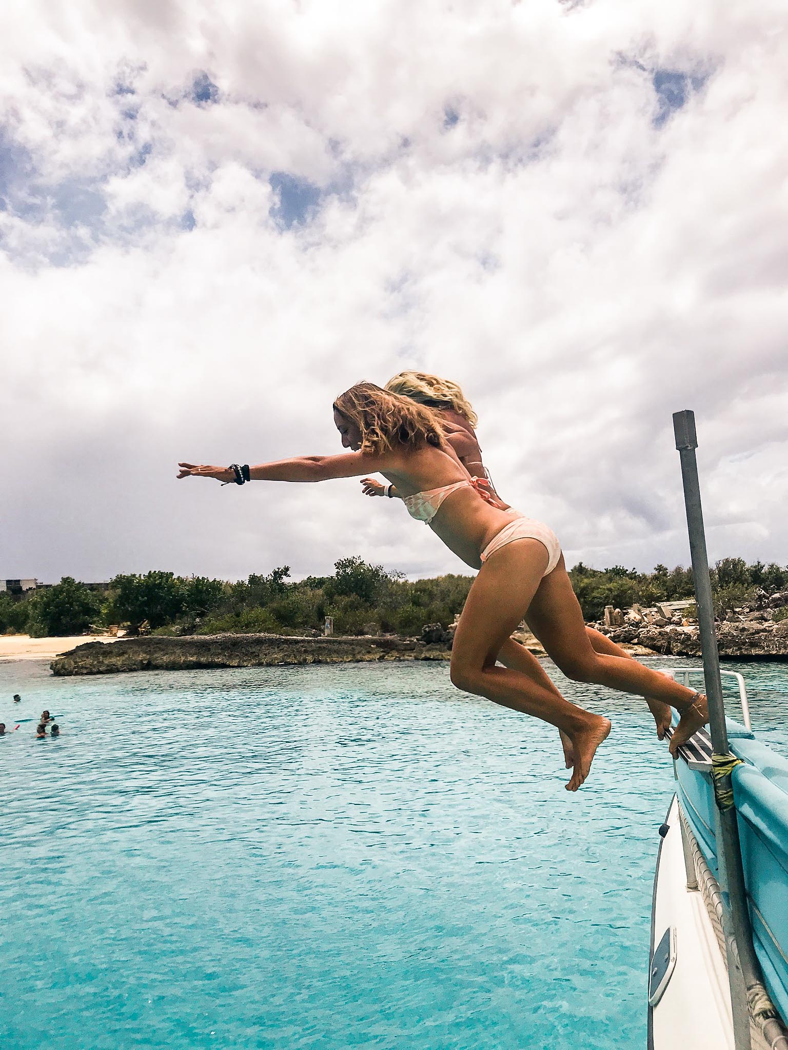 Two girls jumping of Random Wind yacht into the ocean