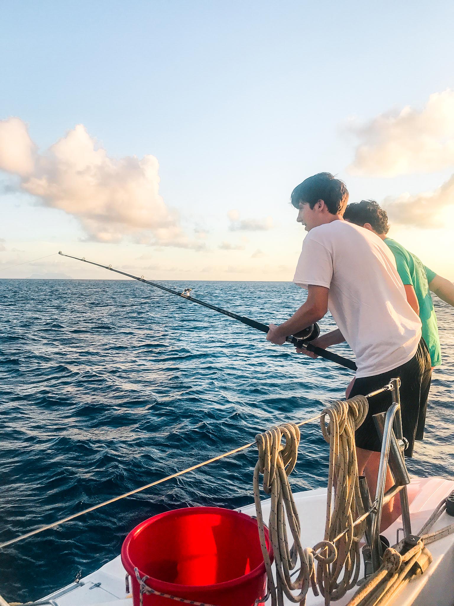 two people fishing off the side of a boat