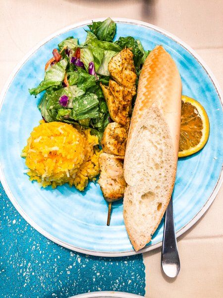 chicken skewer with french bread, rice, and salad on plate