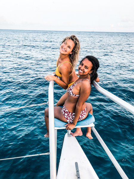 Two young women sitting at front of Random Wind catamaran yacht